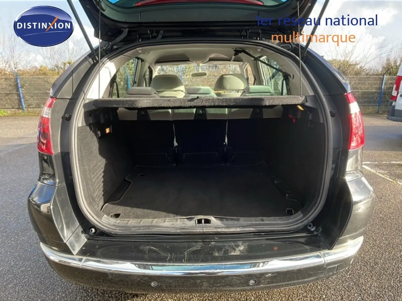 Coffre ouvert vu de l'arrière d'une Citroën C4 Picasso noire métal de 2008, montrant l'espace de chargement vide.