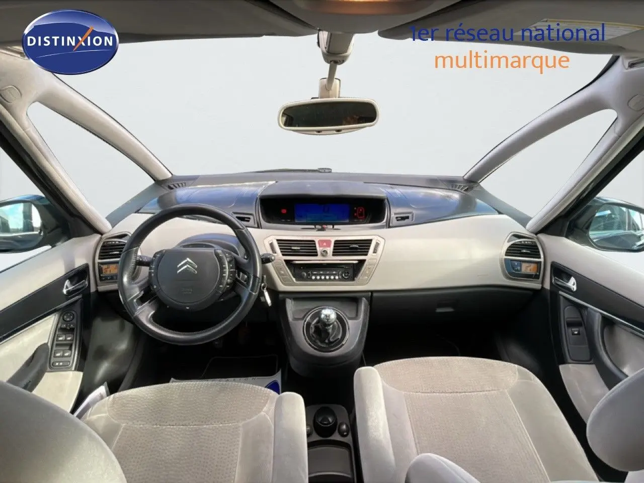 Vue intérieure avant de la Citroën C4 Picasso 2008, tableau de bord beige et noir avec volant cuir et levier de vitesse manuel.