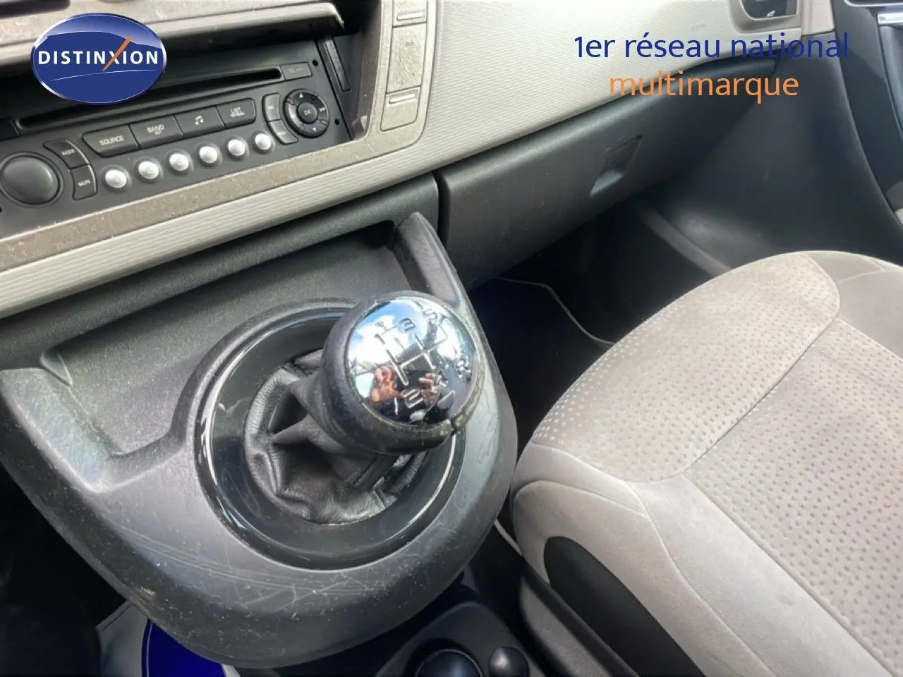 Gros plan sur le levier de vitesses manuel et la console centrale du Citroën C4 Picasso noir métal, intérieur tissu beige.