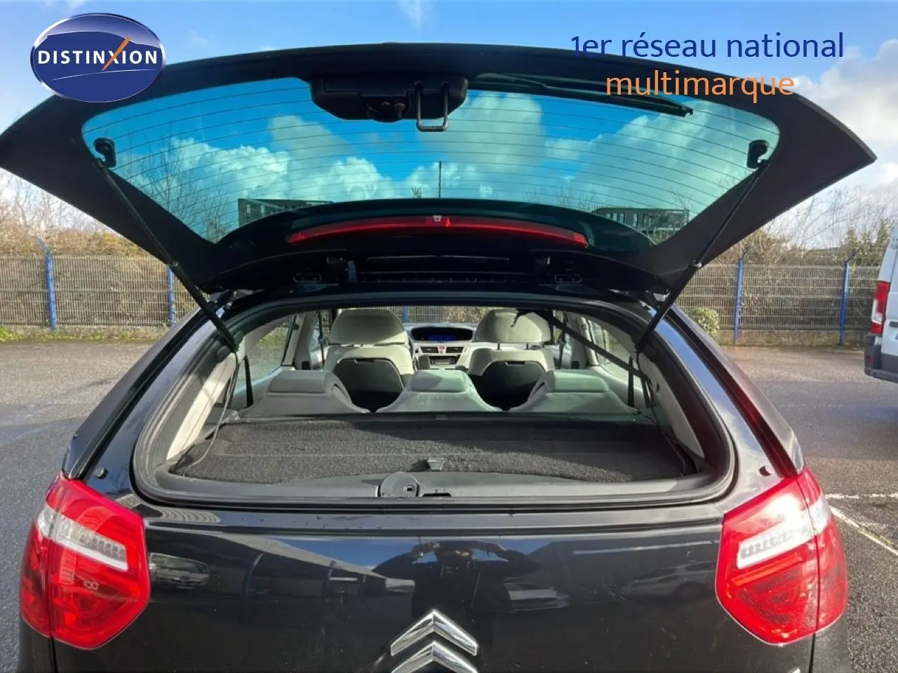 Vue arrière ouverte d'une Citroën C4 Picasso noire métal, montrant l'intérieur et le hayon relevé en extérieur.
