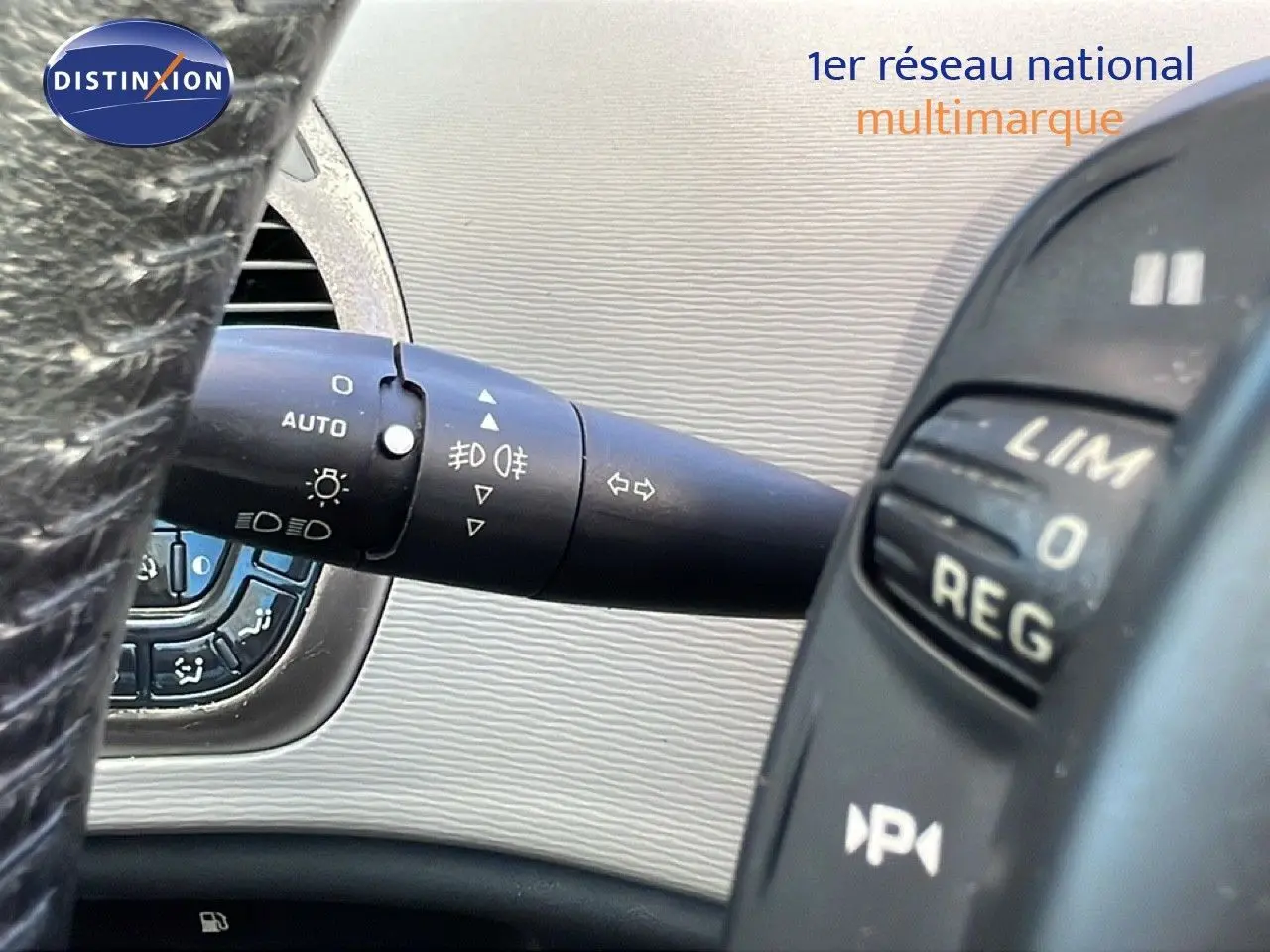 Gros plan sur la manette de clignotant et commandes au volant d'une Citroën C4 Picasso noire, intérieur beige.