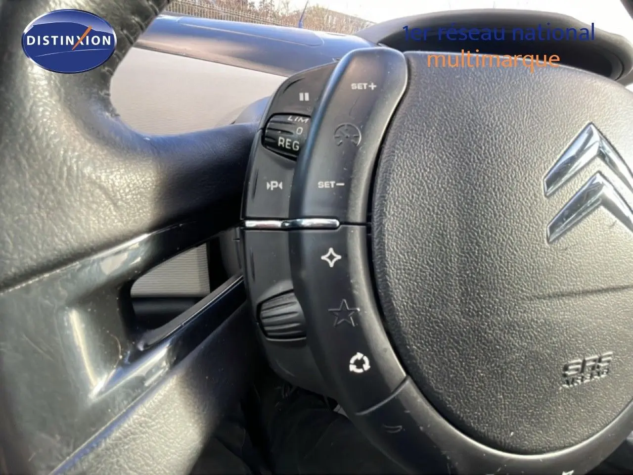 Gros plan sur le volant en cuir noir du Citroën C4 Picasso 2008, montrant les commandes intégrées côté gauche.