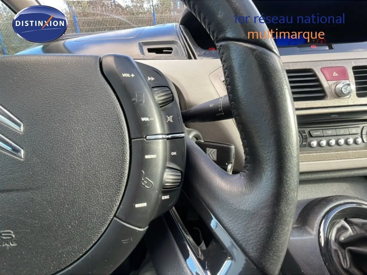 Gros plan sur le volant cuir noir et la console centrale beige du Citroën C4 Picasso 2008, version Exclusive.
