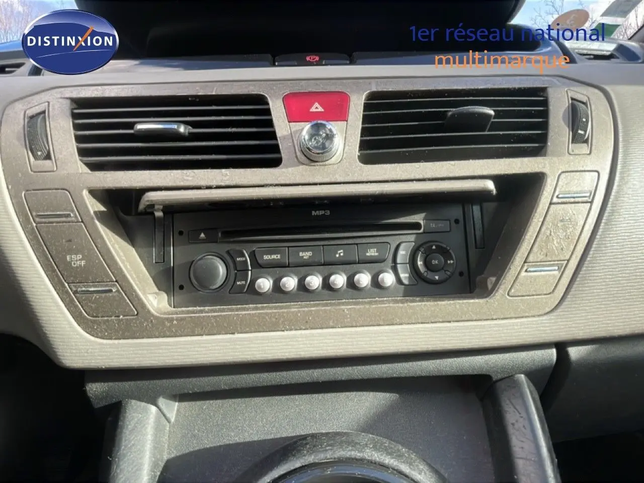 Vue rapprochée du tableau de bord beige et noir du Citroën C4 Picasso 2008 avec autoradio MP3 et commandes centrales.