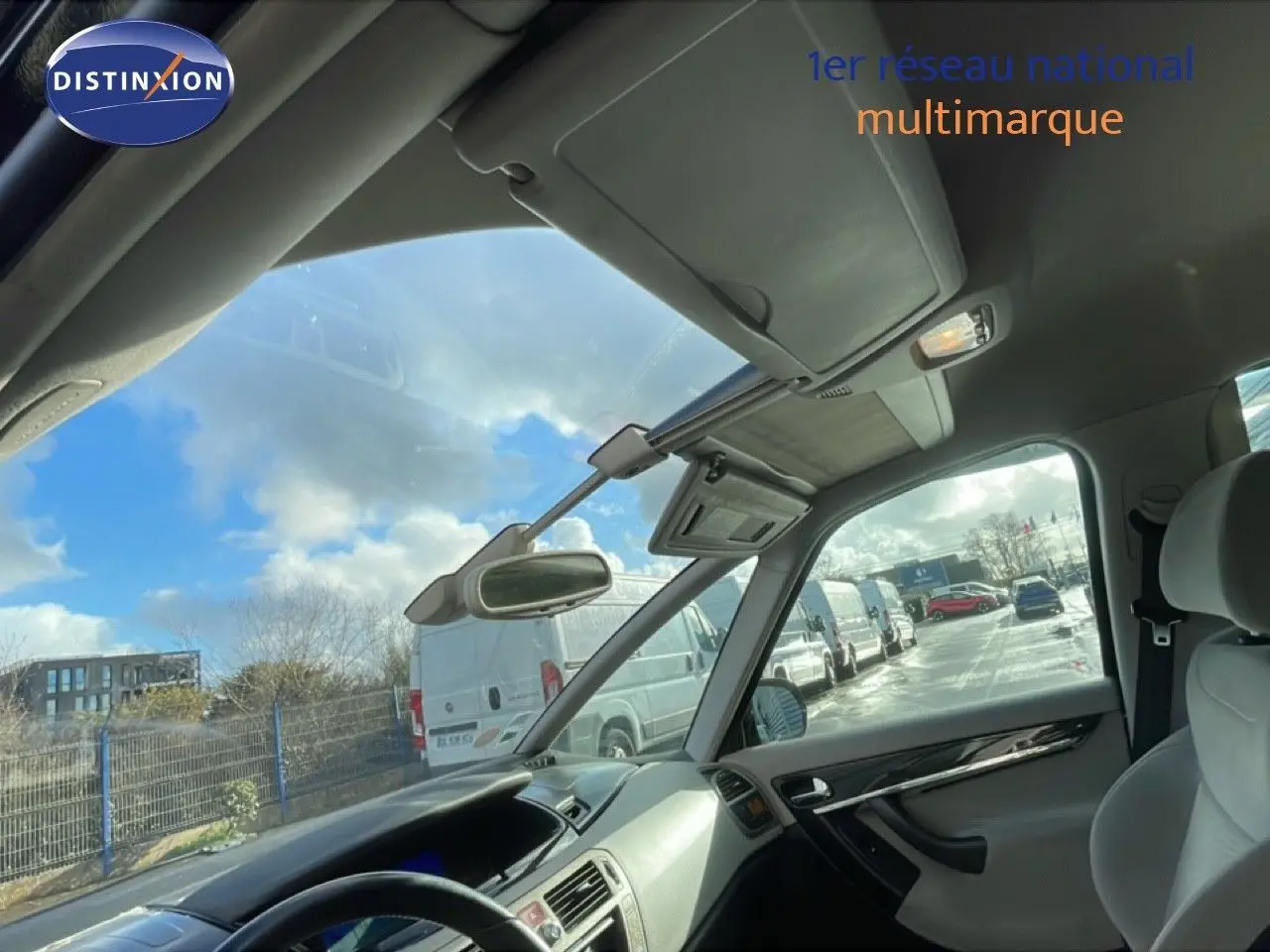 Vue intérieure côté conducteur de la Citroën C4 Picasso noire métal, montrant le tableau de bord et le toit panoramique.