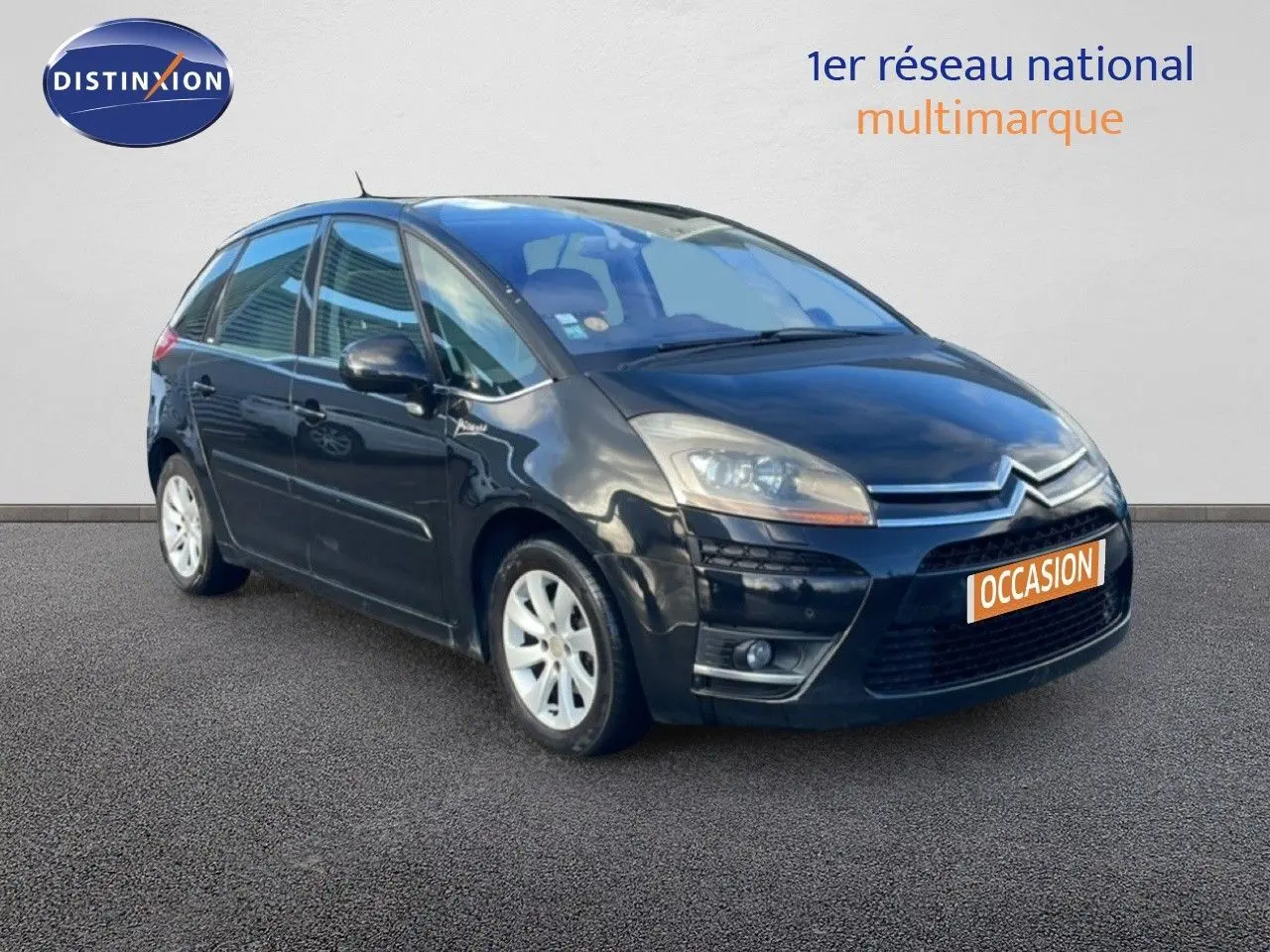 Citroën C4 Picasso noir métal en 3/4 avant droit, avec jantes alliage et calandre distinctive.