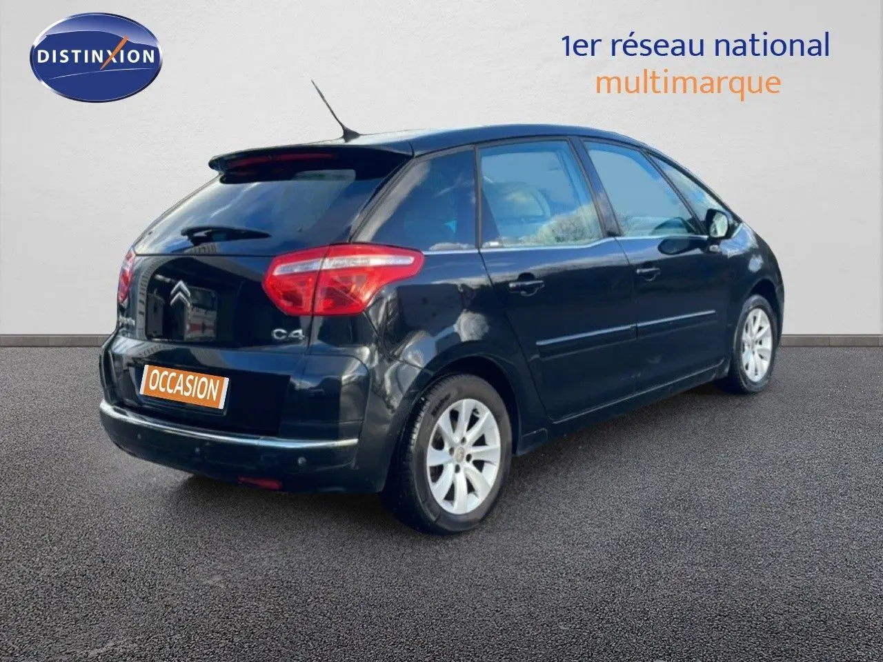 Vue 3/4 arrière droite d'une Citroën C4 Picasso noire métal de 2008 avec feux arrière rouges et jantes alliage argentées.