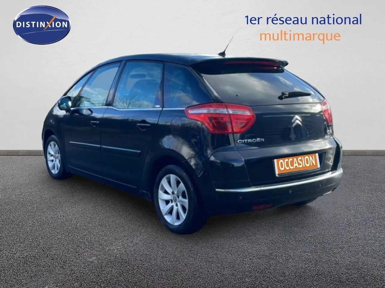 Vue 3/4 arrière droite d'une Citroën C4 Picasso noire métal de 2008 avec jantes alliage et toit vitré.