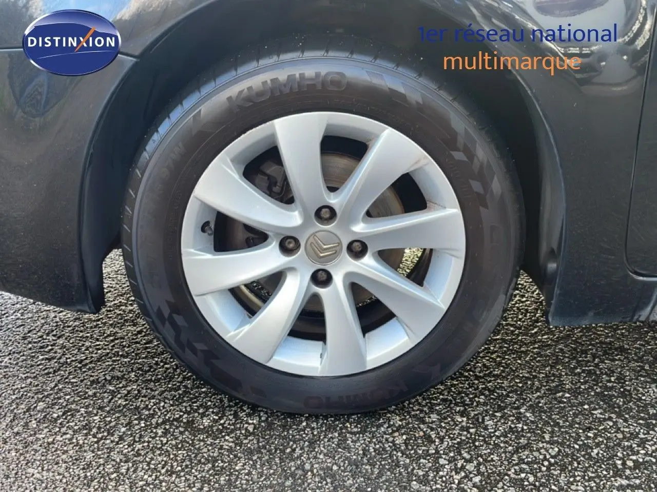Gros plan sur la roue avant gauche d'une Citroën C4 Picasso noire métallisée avec jante alliage 16 pouces.