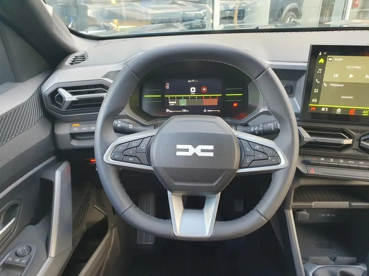 Vue intérieure centrée sur le volant multifonction et le tableau de bord digital du Dacia Duster 2026.