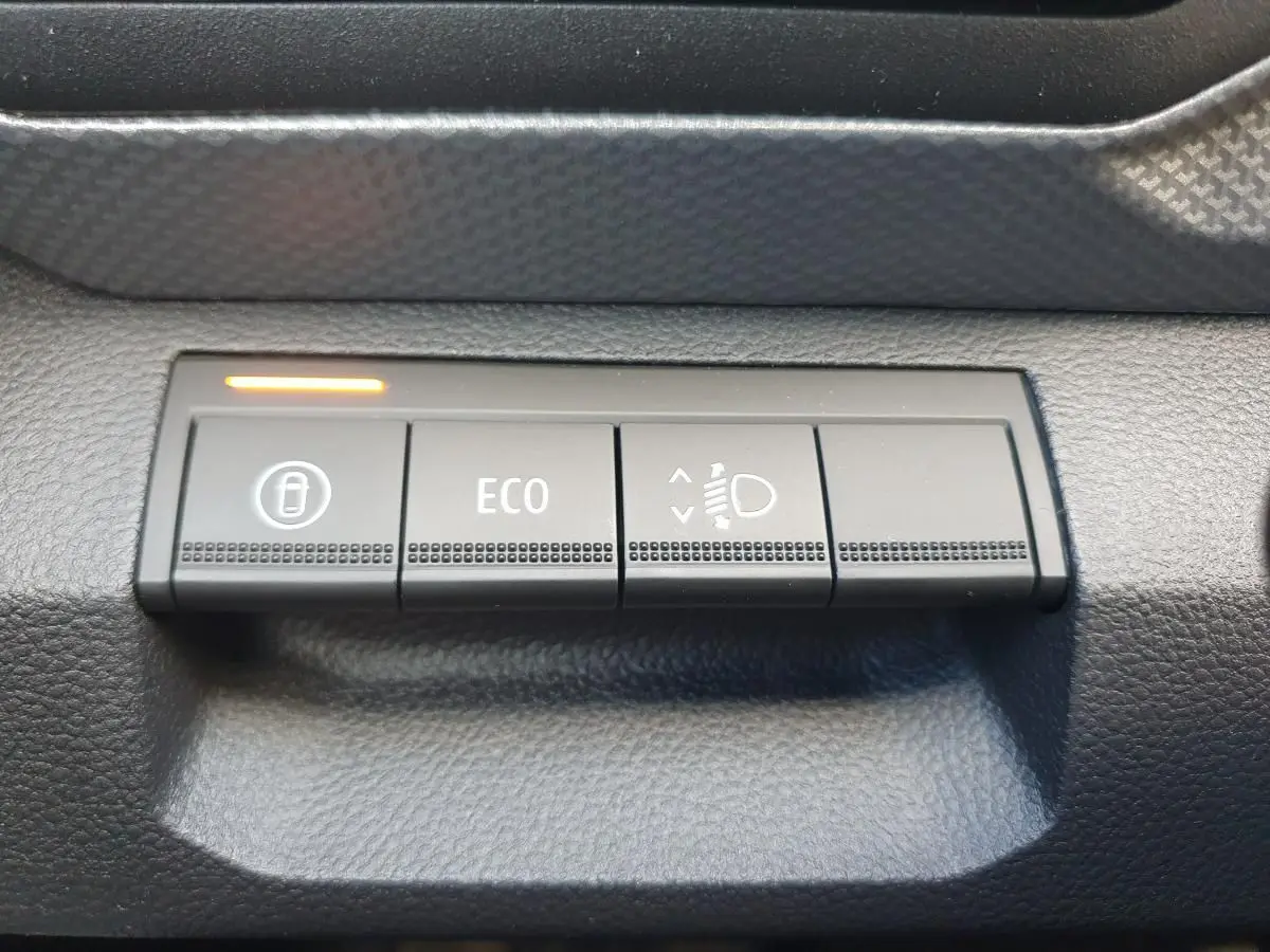 Boutons de commande du tableau de bord du Dacia Duster 2026, vue rapprochée sur les fonctions verrouillage, mode ECO et réglage des phares.