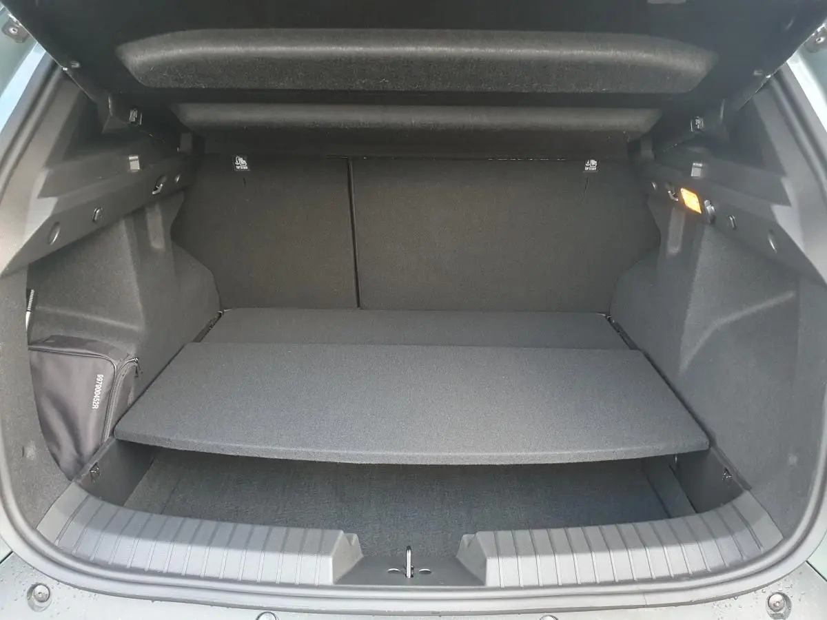 Coffre ouvert du Dacia Duster 2026, vue arrière, montrant la tablette de séparation et l'intérieur noir du coffre.