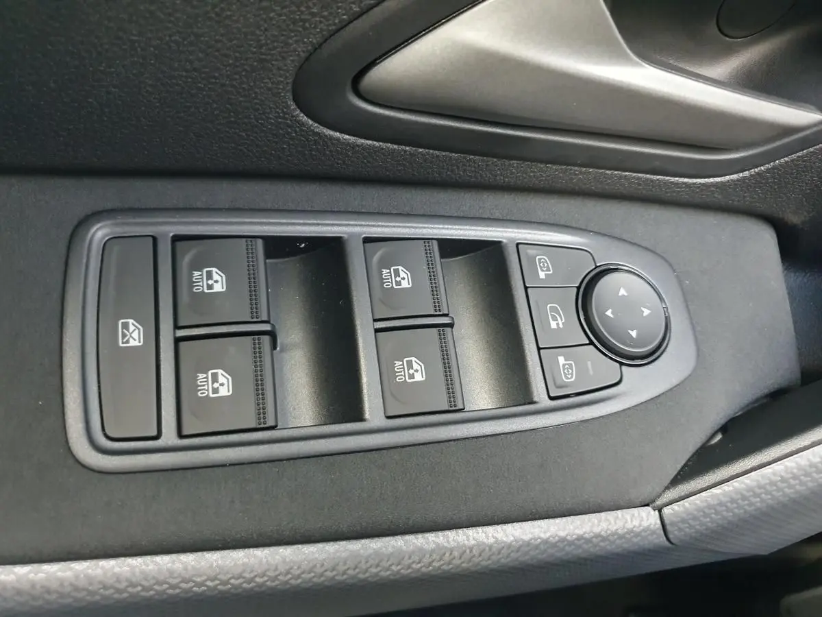 Commande des vitres électriques et réglages des rétroviseurs sur la porte côté conducteur du Dacia Duster 2026.