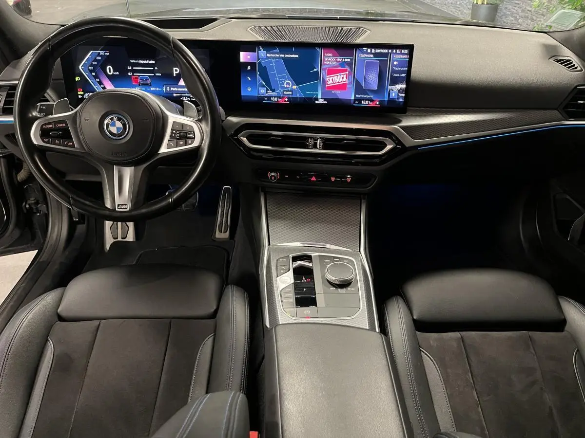 Vue intérieure avant de la BMW Série 3 G21 M Sport 320e noire, avec tableau de bord numérique et écran tactile large.