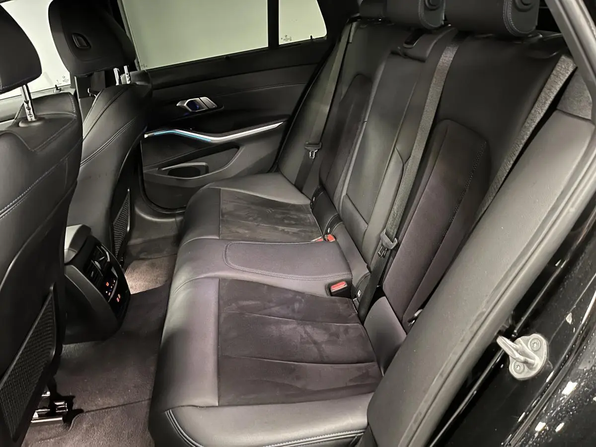 Vue intérieure côté droit sur la banquette arrière en cuir noir avec détails Alcantara de la BMW Série 3 Touring 320e M Sport.