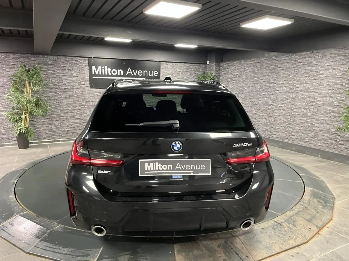 Vue arrière d'une BMW Série 3 320e Touring noire avec double sortie d'échappement et feux arrière LED.