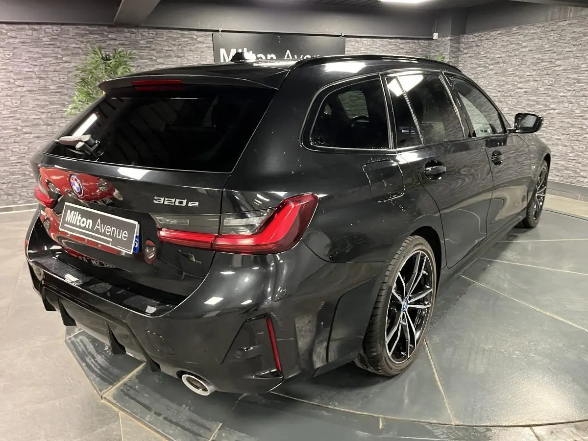 BMW Série 3 320e Touring noire vue en 3/4 arrière droit, avec jantes M Sport bicolores et feux LED distinctifs.