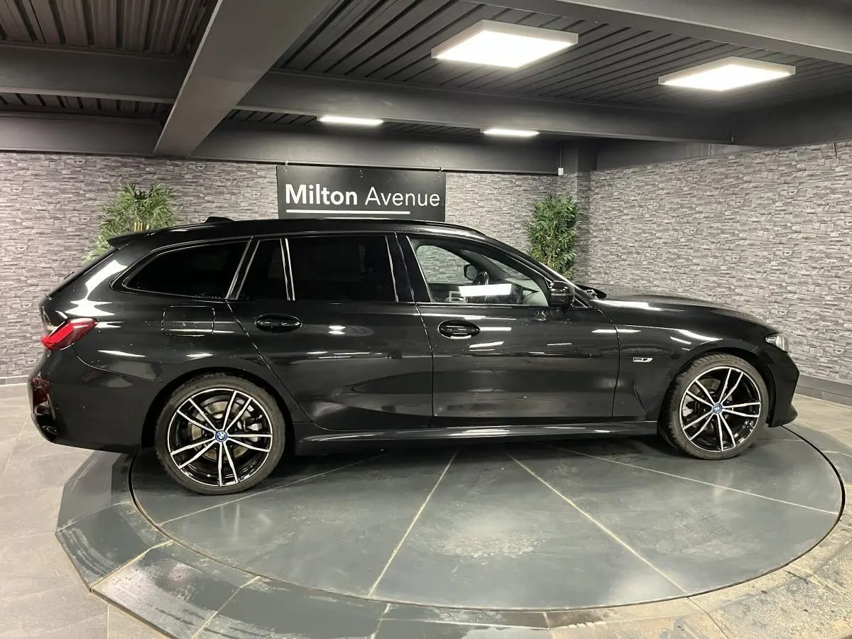 BMW Série 3 320e Touring noire vue de profil côté gauche, avec jantes 19 pouces bicolores et toit ouvrant panoramique.