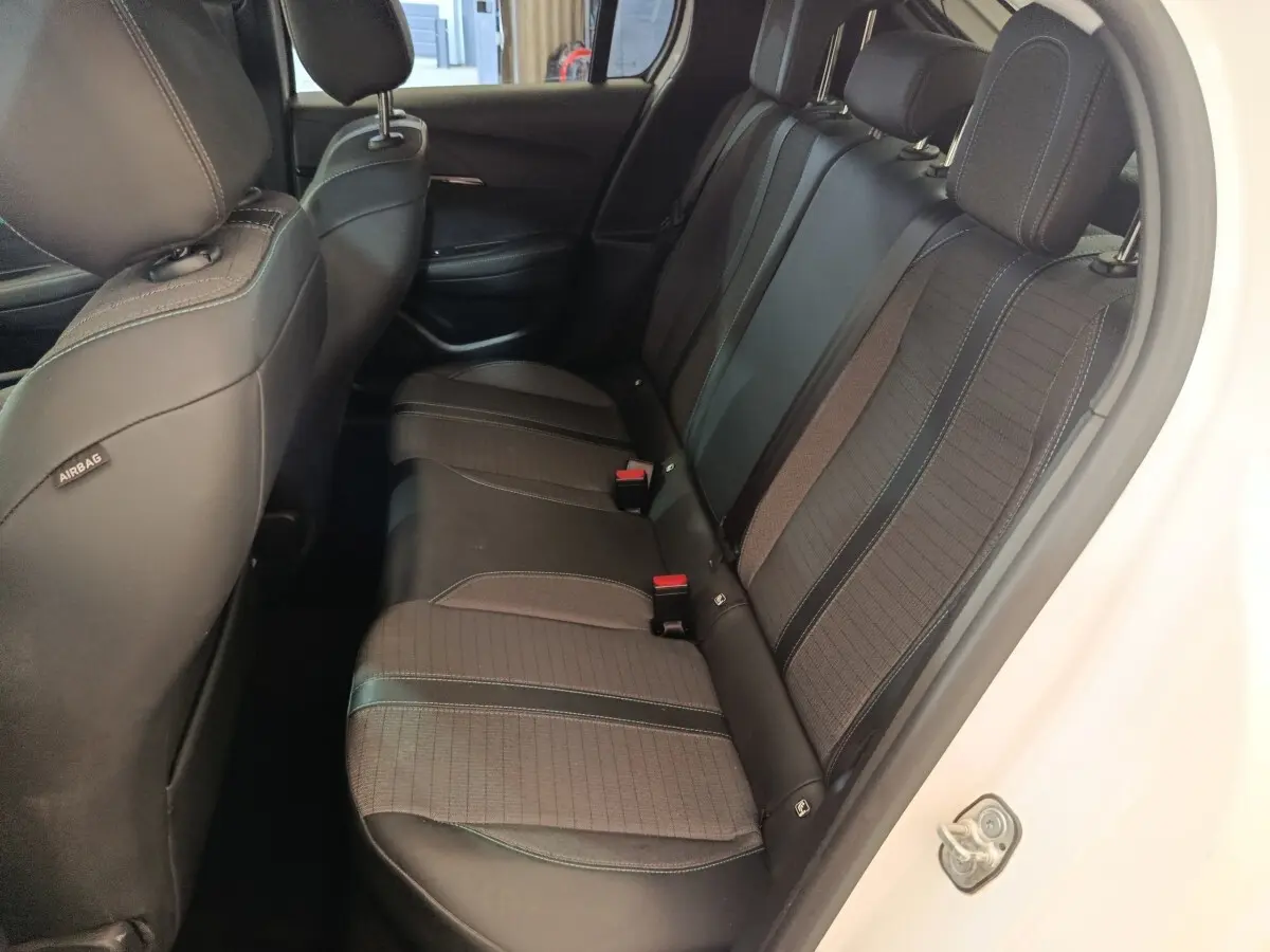 Vue côté droit de la banquette arrière noire et grise du Peugeot 208 blanc, avec appuie-têtes et ceintures visibles.