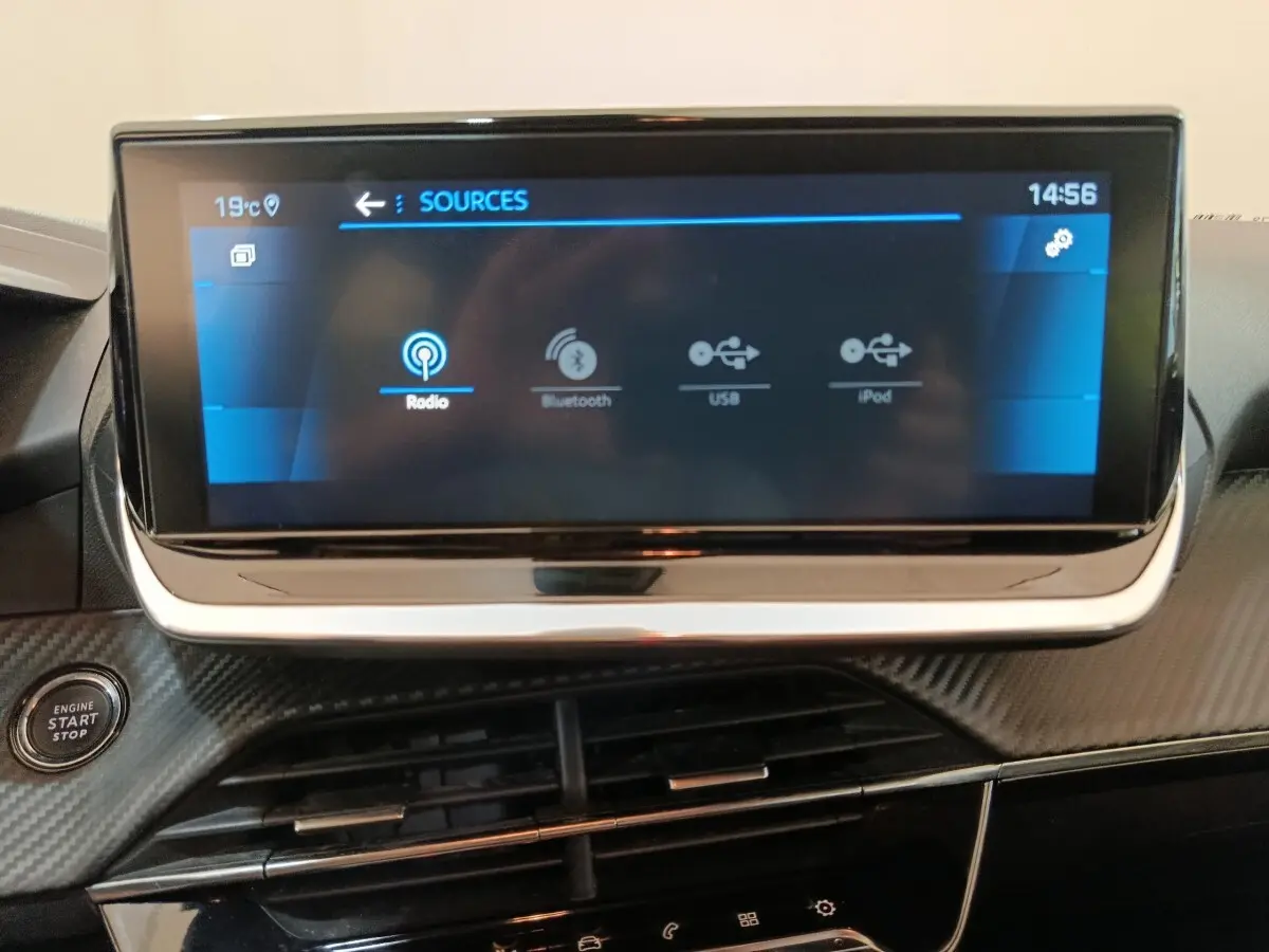 Écran tactile central 10 pouces de la Peugeot 208 PureTech 100, avec bouton démarrage et finition carbone noire.
