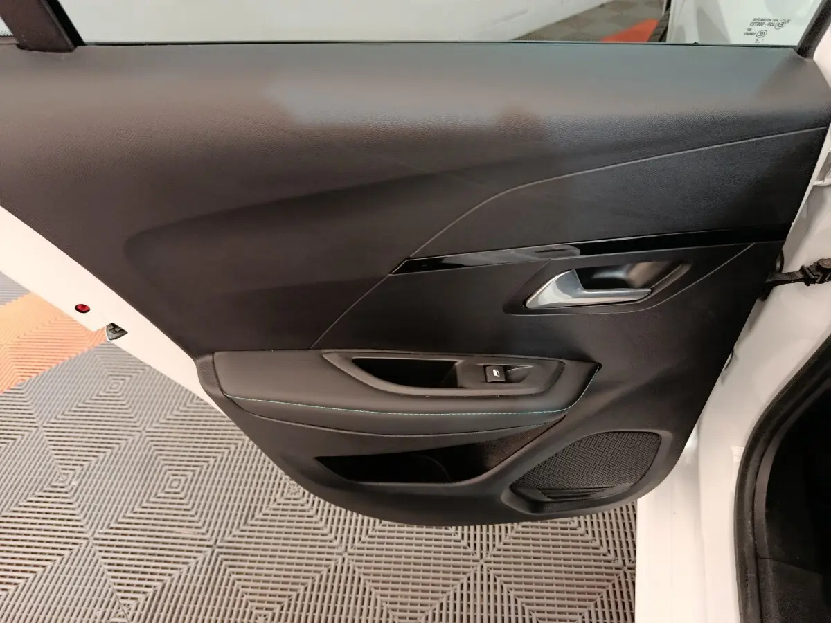 Vue rapprochée de la porte arrière droite noire avec poignée argentée d'une Peugeot 208 blanche 2021.
