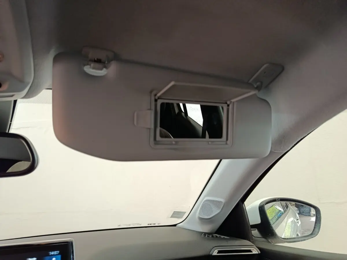 Intérieur de la Peugeot 208 blanc, vue sur le pare-soleil avec miroir et rétroviseur côté droit visible.