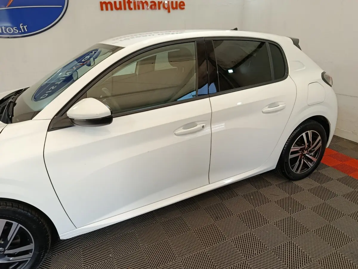 Peugeot 208 blanc vue de profil côté gauche, avec jantes alliage noires et vitres teintées.