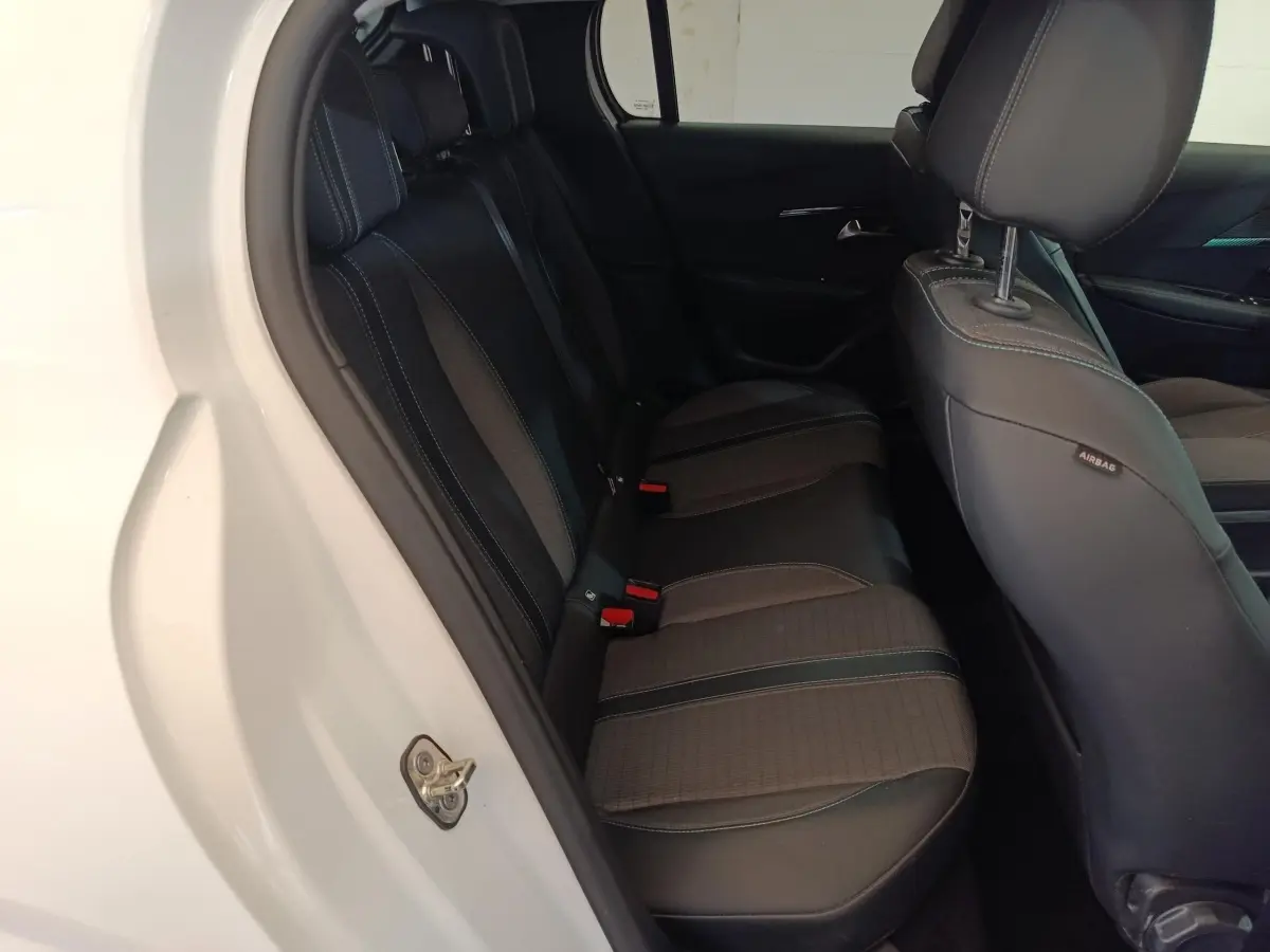 Vue intérieure côté gauche sur la banquette arrière noire de la Peugeot 208 blanche PureTech 100 S&S Allure Business.