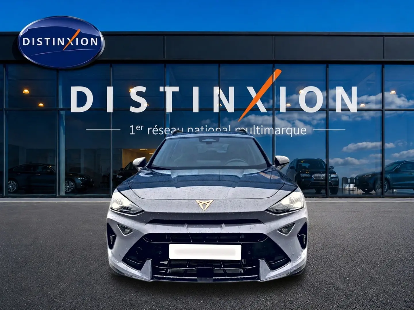 Vue frontale d'un CUPRA Formentor gris graphene 2026 avec logo distinctif sur calandre, devant showroom Distinxion.