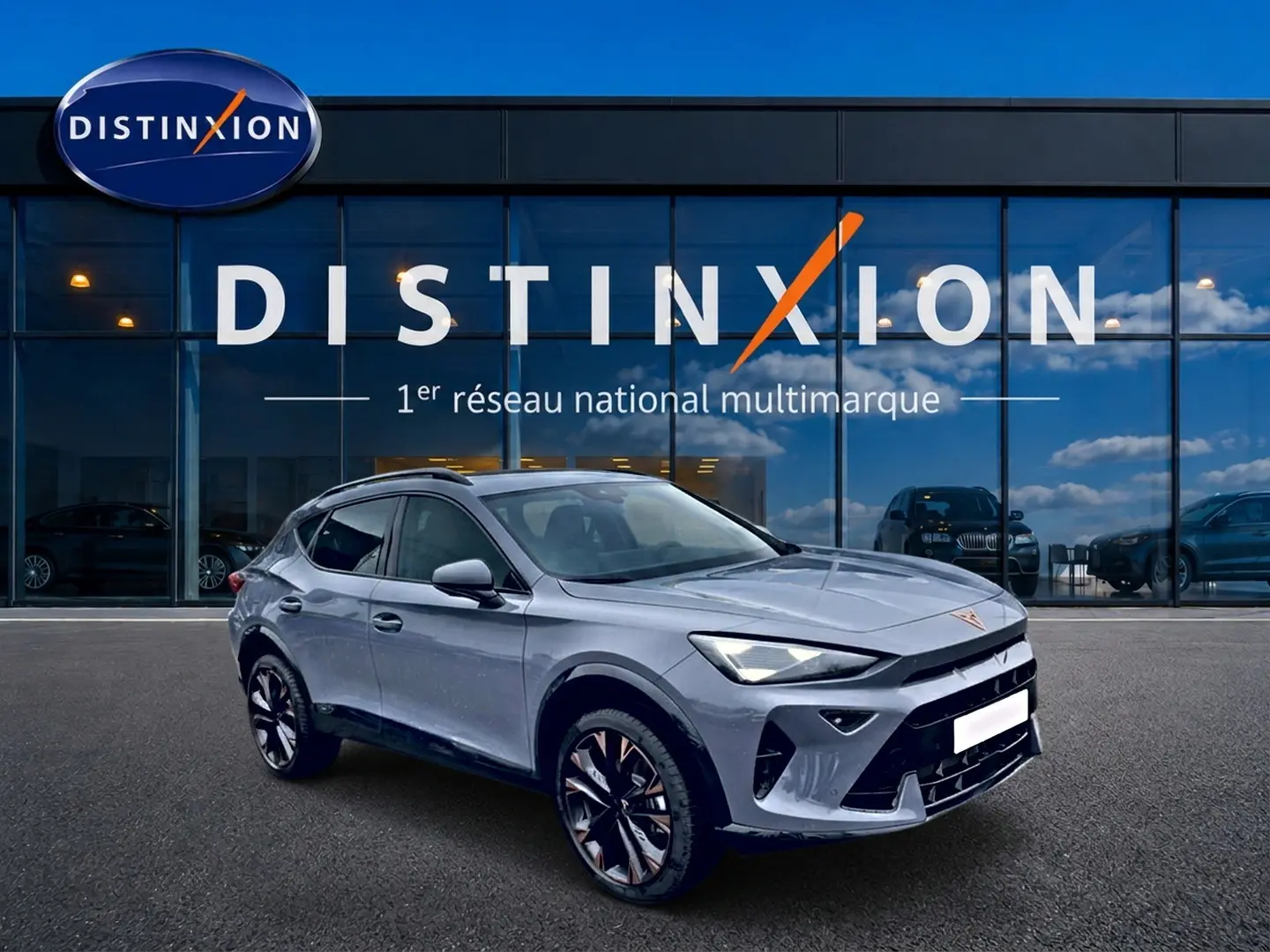 Vue 3/4 avant d'un CUPRA Formentor gris graphene avec jantes noires et détails cuivrés, devant une vitrine Distinxion.