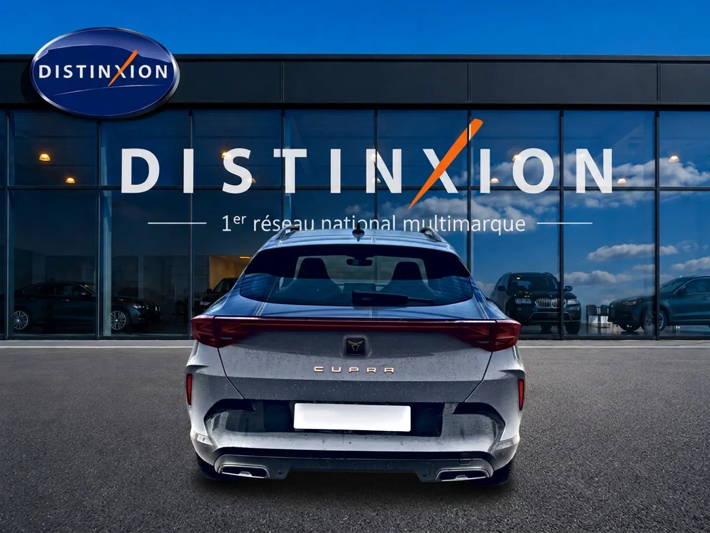 Vue arrière du CUPRA Formentor gris graphene 2026 avec feux LED et double sortie d'échappement, devant un showroom Distinxion.