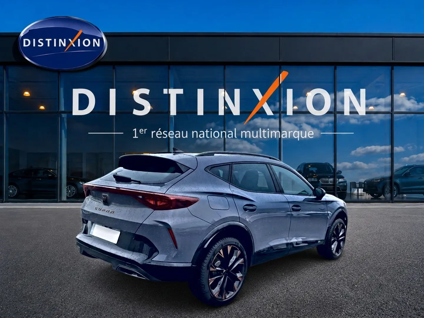 Vue 3/4 arrière droite d'une CUPRA Formentor gris graphene avec jantes noires et détails cuivrés, devant une vitrine Distinxion.