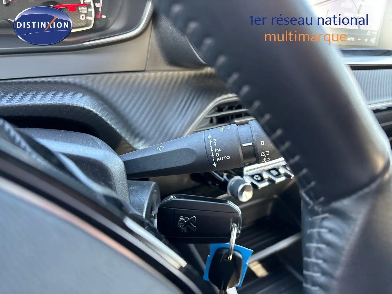 Gros plan sur la clé de contact Peugeot 2008 gris Artense insérée près du volant et des commandes d'essuie-glace.