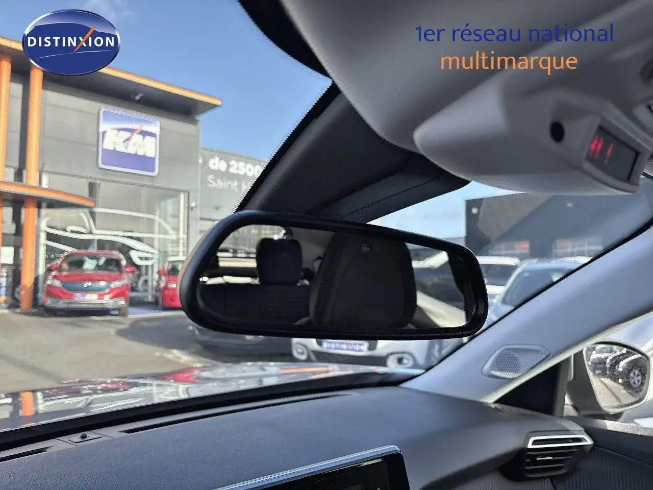 Vue intérieure du tableau de bord et rétroviseur central d'une Peugeot 2008 gris Artense, avec reflet du siège arrière visible.