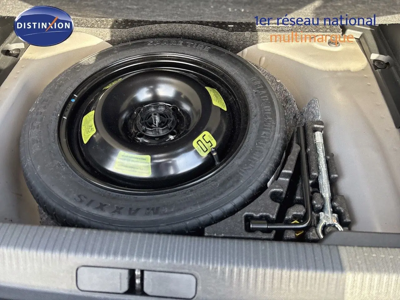 Roue de secours noire et outils de changement dans le coffre d'un Peugeot 2008 gris Artense 2021.