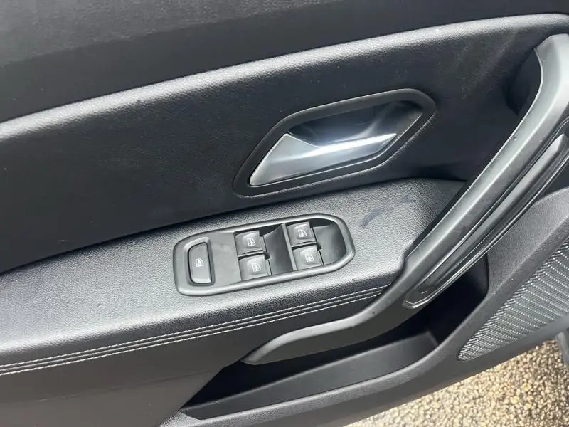 Gros plan sur la porte côté gauche intérieure du Dacia Duster gris Comète, avec commandes des vitres et poignée argentée.