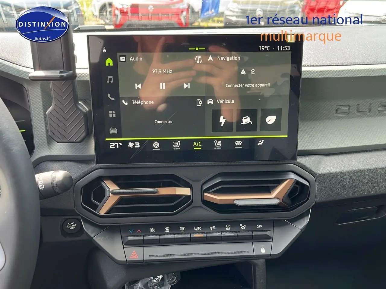 Vue intérieure du tableau de bord du Dacia Duster 2025 avec écran tactile et aérateurs hexagonaux noirs et bronze.