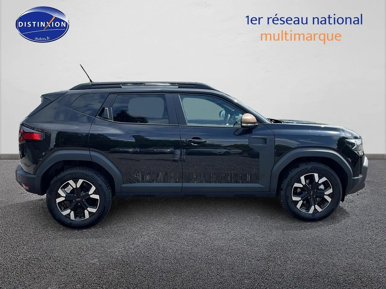 Profil latéral droit d'un Dacia Duster noir 2025 avec jantes alu et rétroviseur couleur bronze.