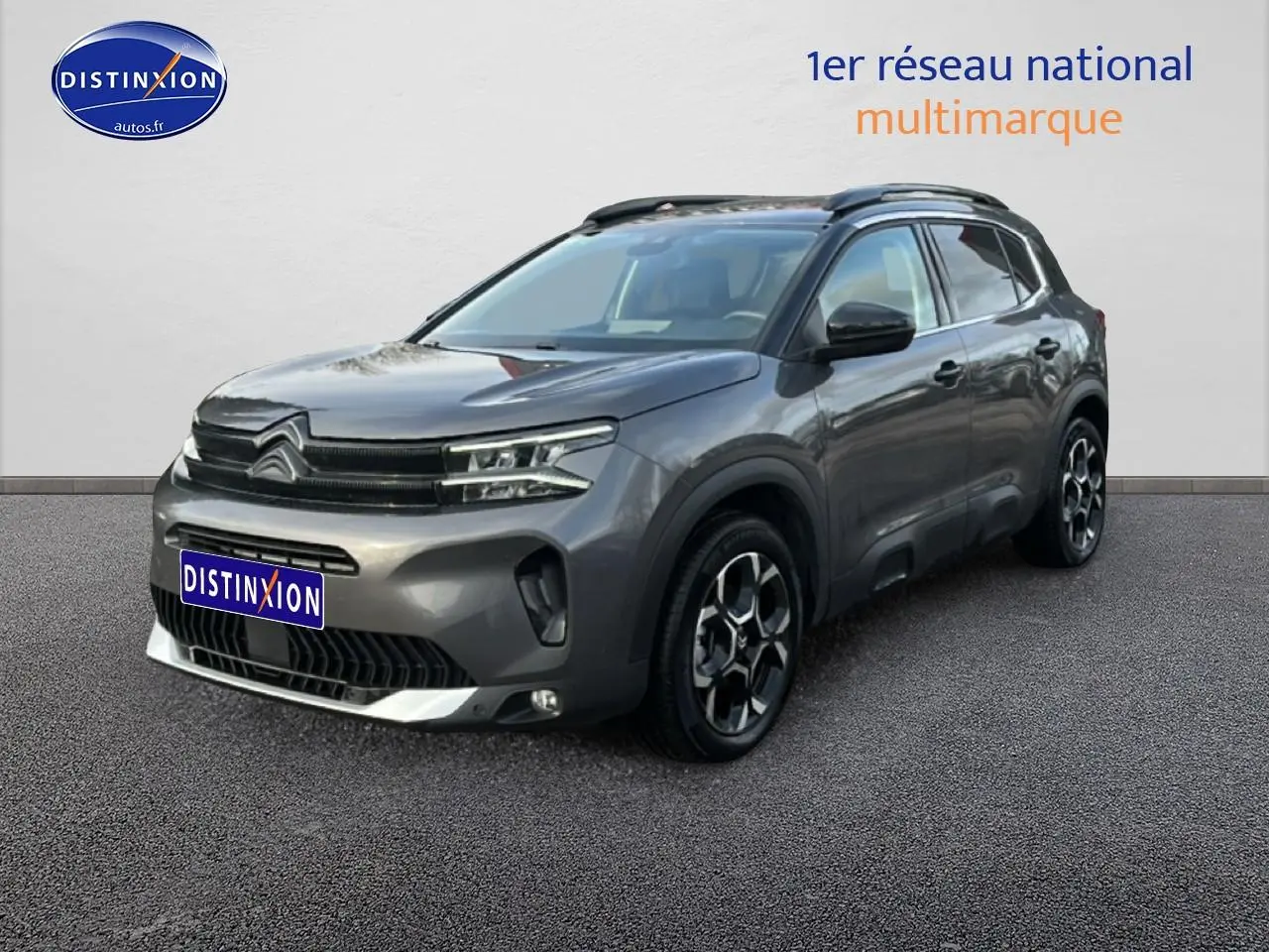 Citroën C5 Aircross gris métallisé vue 3/4 avant droit avec jantes alu et barres de toit noires.