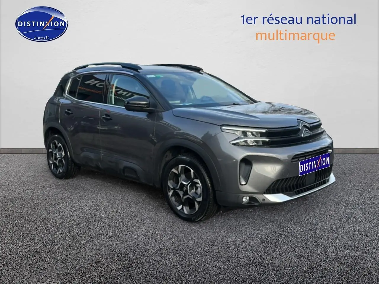 Citroën C5 Aircross gris 3/4 avant droit avec jantes alu et barres de toit visibles sur fond neutre.