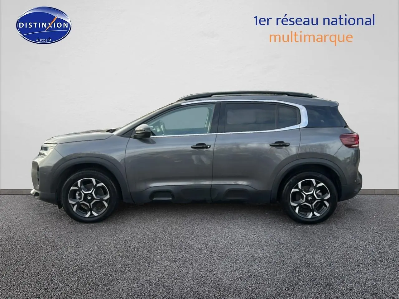 Vue latérale droite d'un Citroën C5 Aircross gris métallisé avec jantes alliage et barres de toit noires.