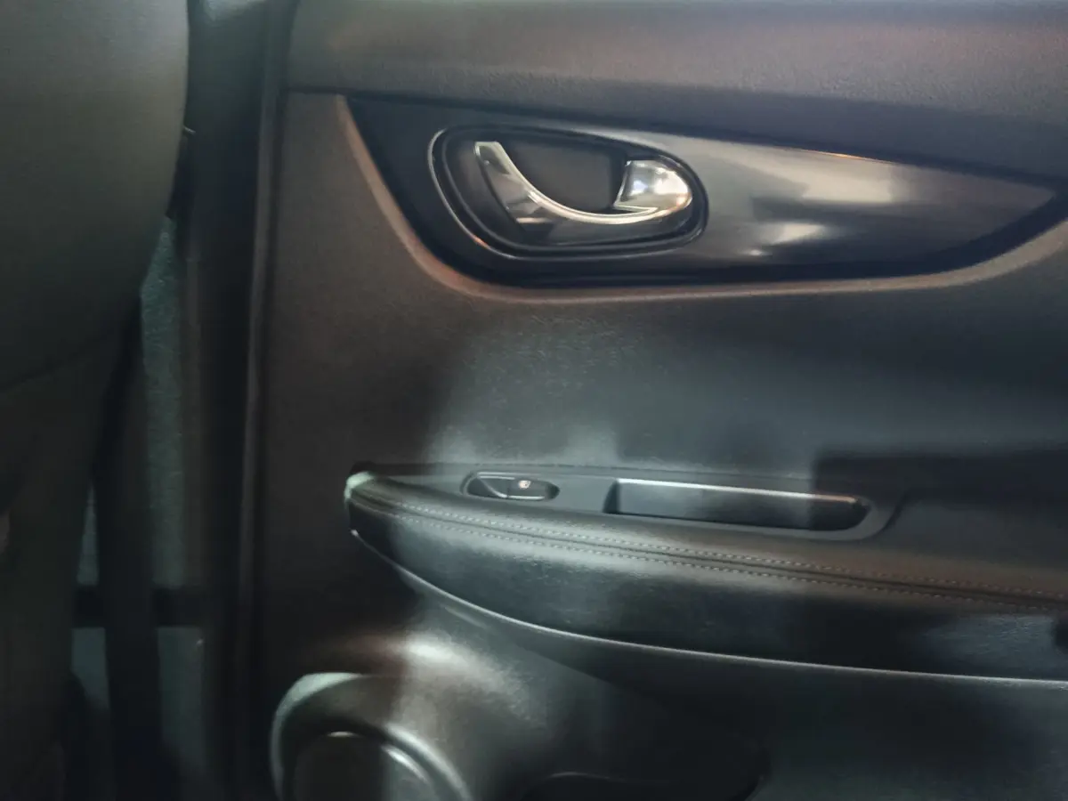 Détail de la porte intérieure côté droit du Nissan Qashqai 1.5 DCI 115 Business Edition, avec poignée chrome et accoudoir noir.