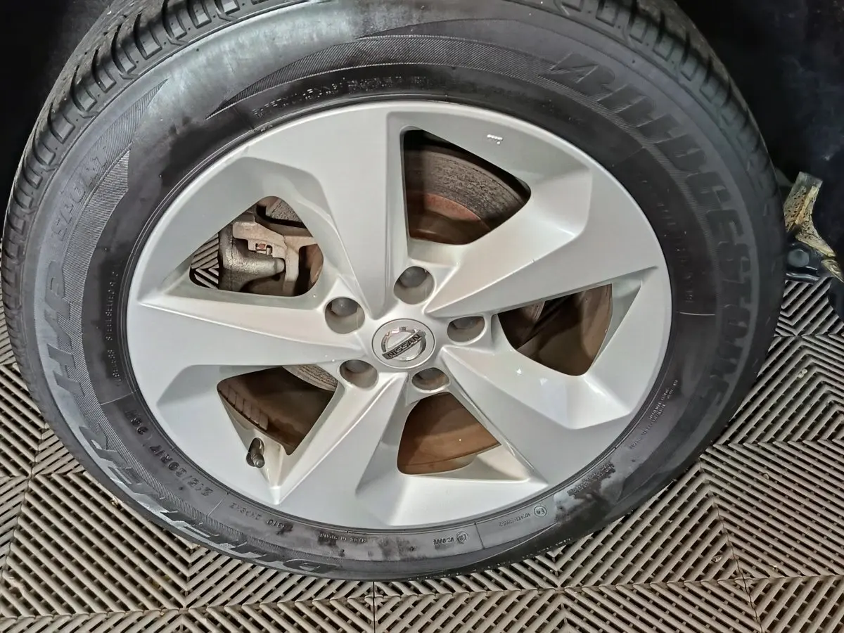Gros plan sur la roue avant droite du Nissan Qashqai gris clair, jante alliage à cinq branches, pneu Bridgestone.