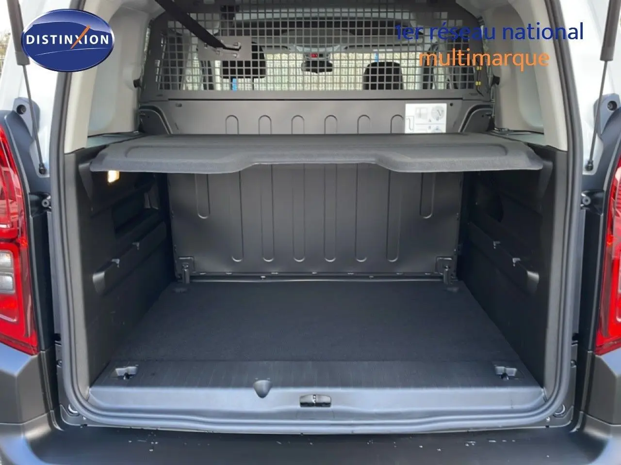 Vue arrière du coffre ouvert du Citroën Berlingo blanc glacier 2025, montrant l’espace de chargement et la grille de séparation.