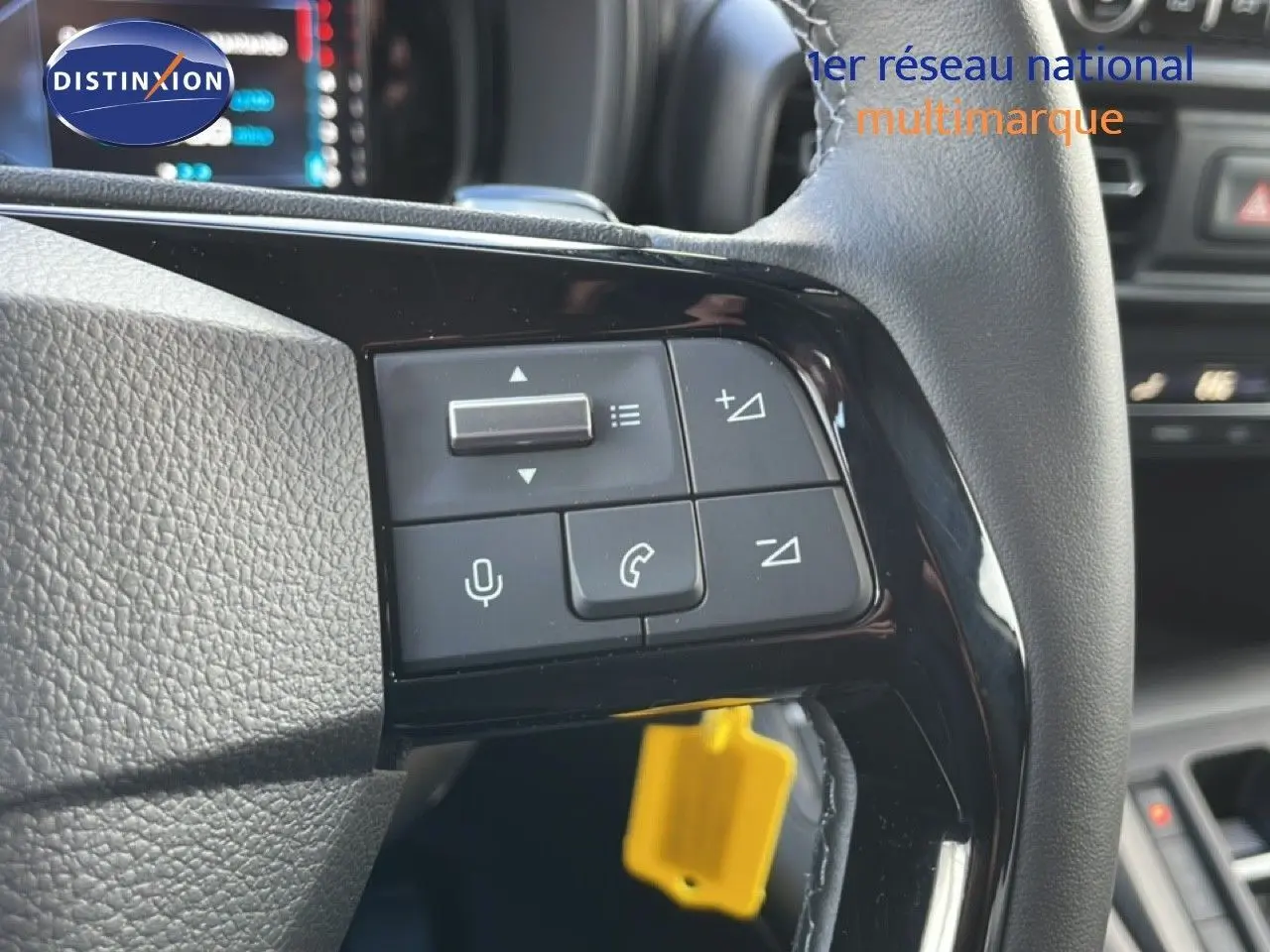 Gros plan sur les commandes du volant côté gauche du Citroën Berlingo blanc glacier, avec boutons de volume et téléphone.