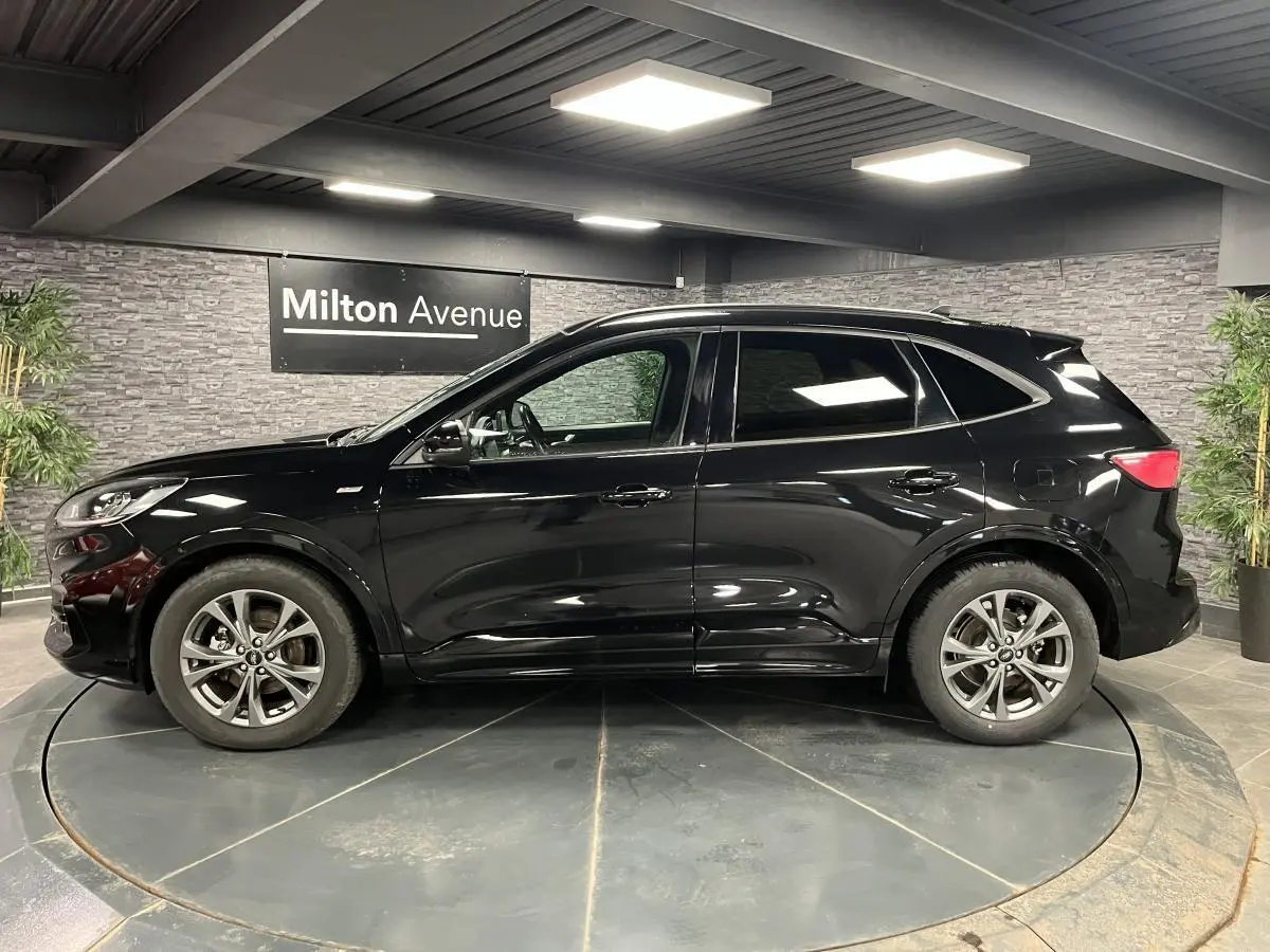 Vue latérale gauche d'un Ford Kuga noir 2022 avec jantes alliage 18 pouces et vitres arrière surteintées.