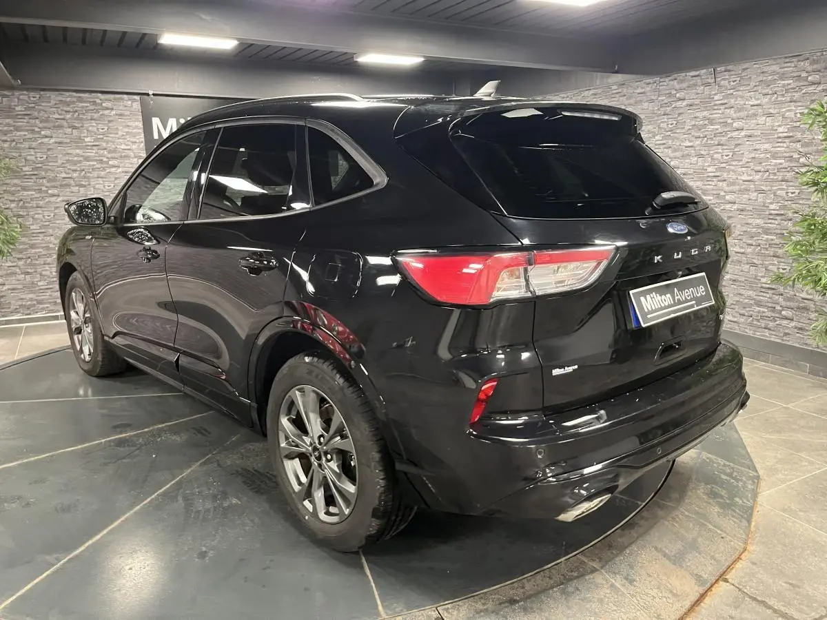 Vue 3/4 arrière droite d'un Ford Kuga noir avec jantes alliage 18 pouces et badges ST-Line visibles.