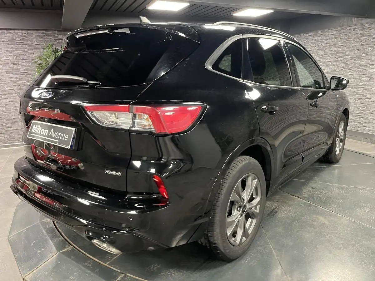 Vue 3/4 arrière droite d'un Ford Kuga noir hybride avec feux arrière LED et jantes alliage 18 pouces.