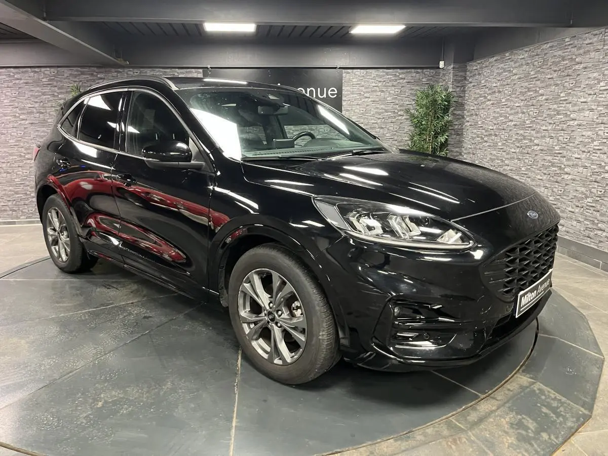 Ford Kuga noir en 3/4 avant droit, avec calandre large et jantes alliage 18 pouces ST-Line visibles.