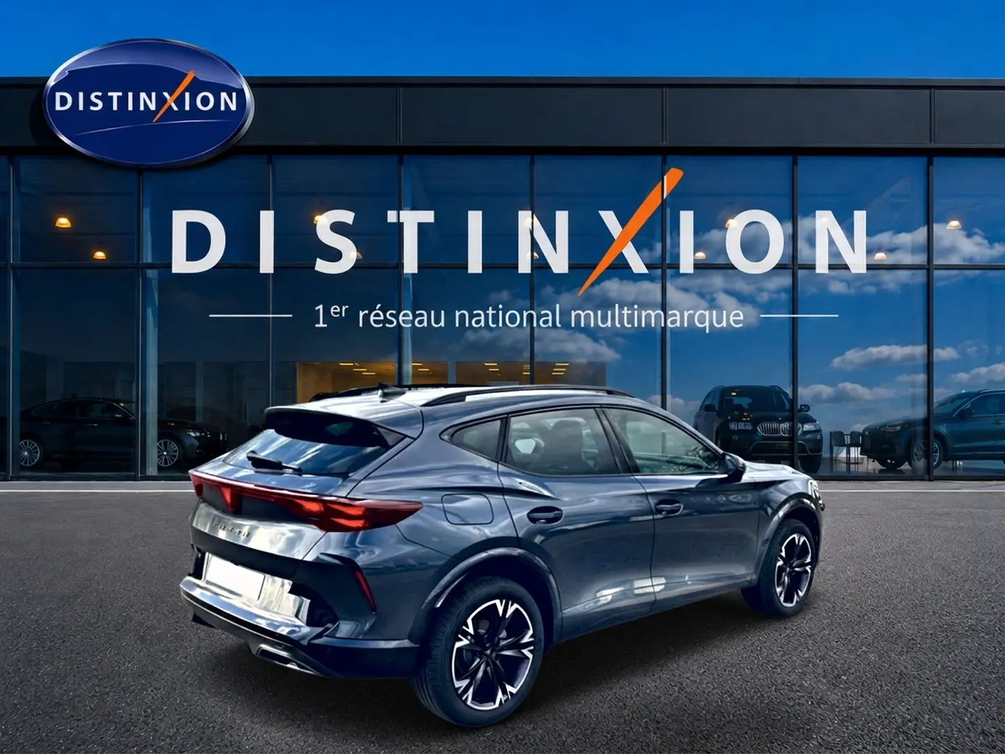 Vue 3/4 arrière droite d'une CUPRA Formentor gris magnétique avec jantes noires et toit panoramique, devant un showroom Distinxion.